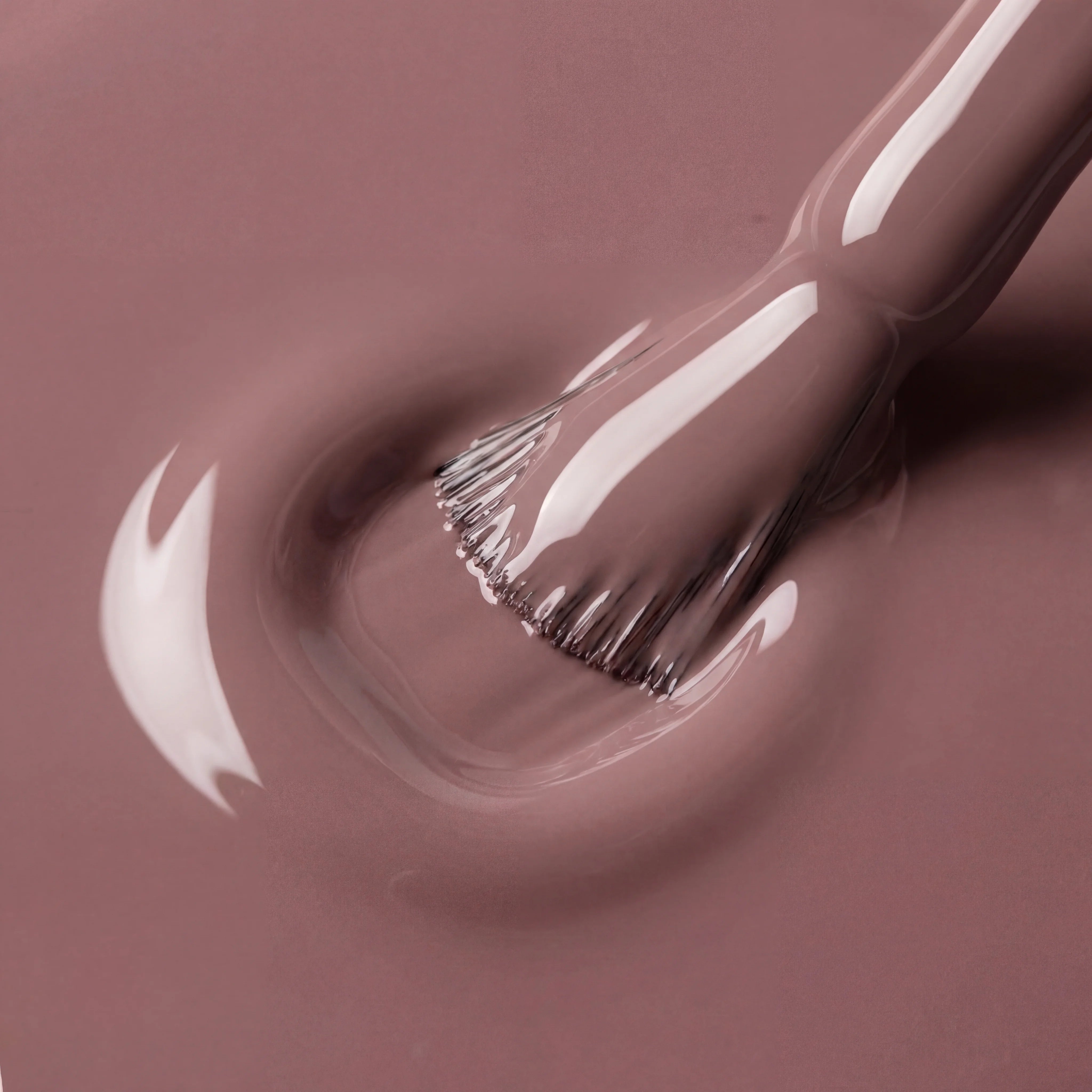 Close-up of a makeup brush with brown nail polish on a matching background