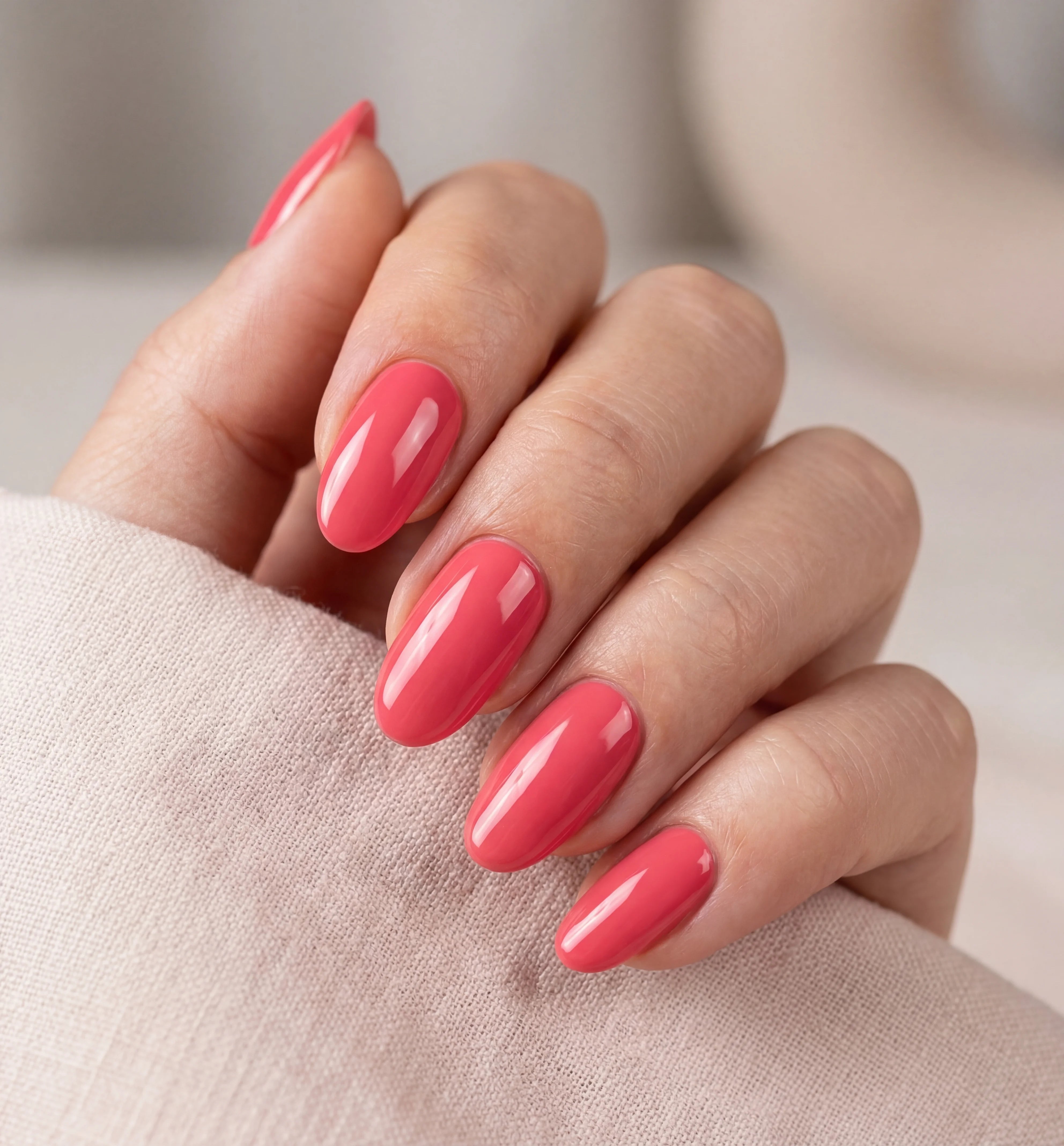Hand with pink nail polish on a neutral background
