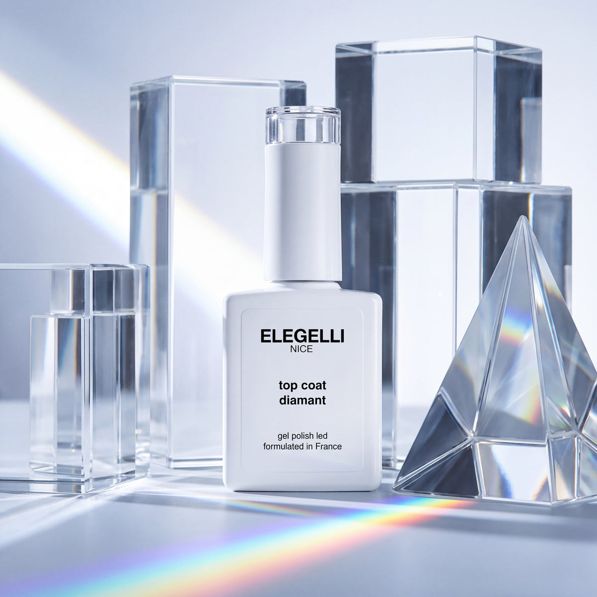 Buteleczka Elegelli Diamond Top Coat wśród przezroczystych szklanych bloków i pryzmatu, który rzuca tęczę